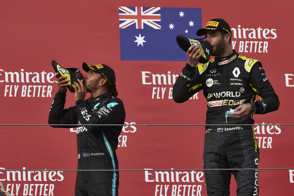 Lewis Hamilton and Daniel Ricciardo drinking champagne from a show