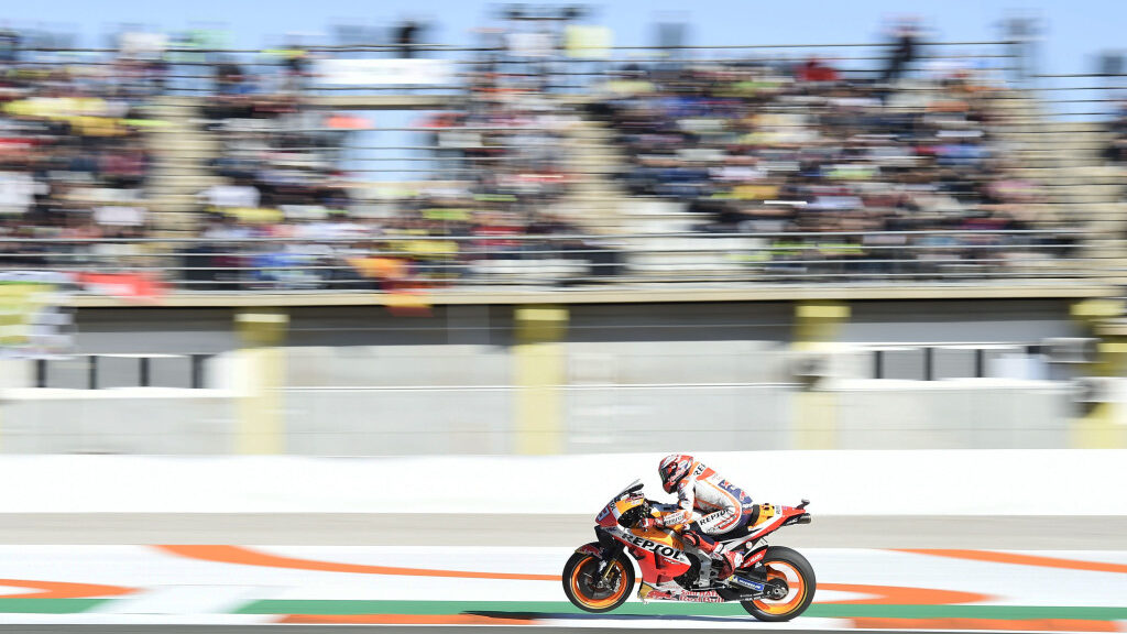 A motobike passes a grandstand at speed