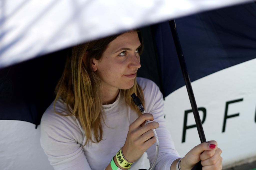 Esmee Hawkey sheltering from the sun under an umbrella before a motor race.