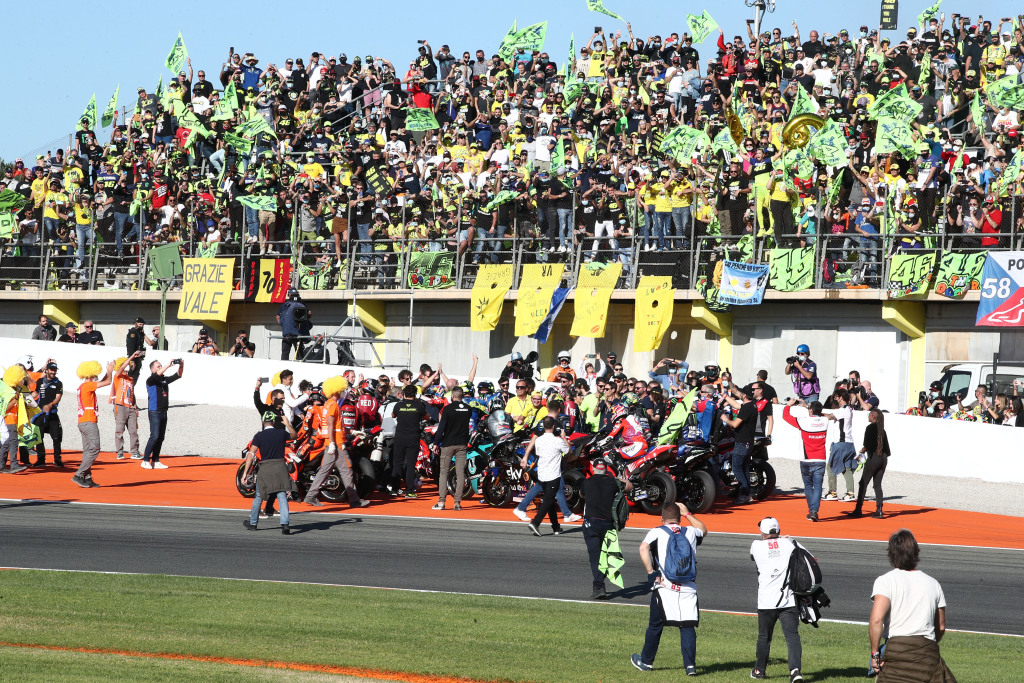 Motorcycle riders gather underneath a grandstand to congratulate Valentino Rossi on his retirement.